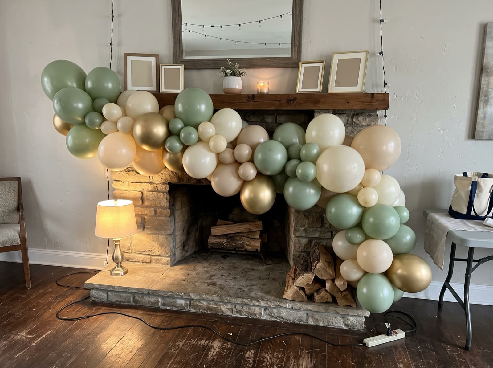 Organic balloon garland in sage, ivory and gold draped over a fireplace mantel in a Houston home