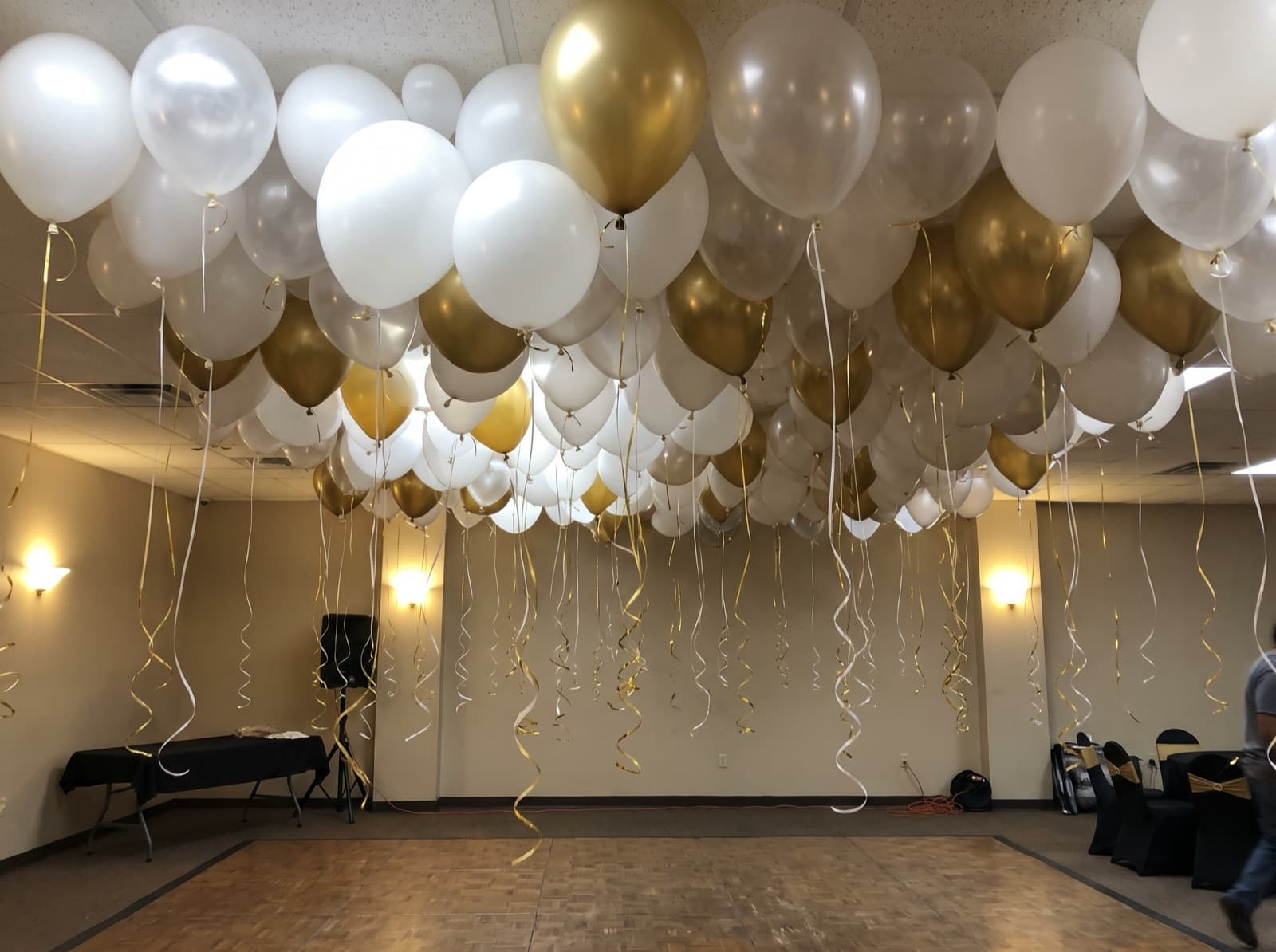 Balloon ceiling of white and gold balloons over a dance floor in a Houston event hall