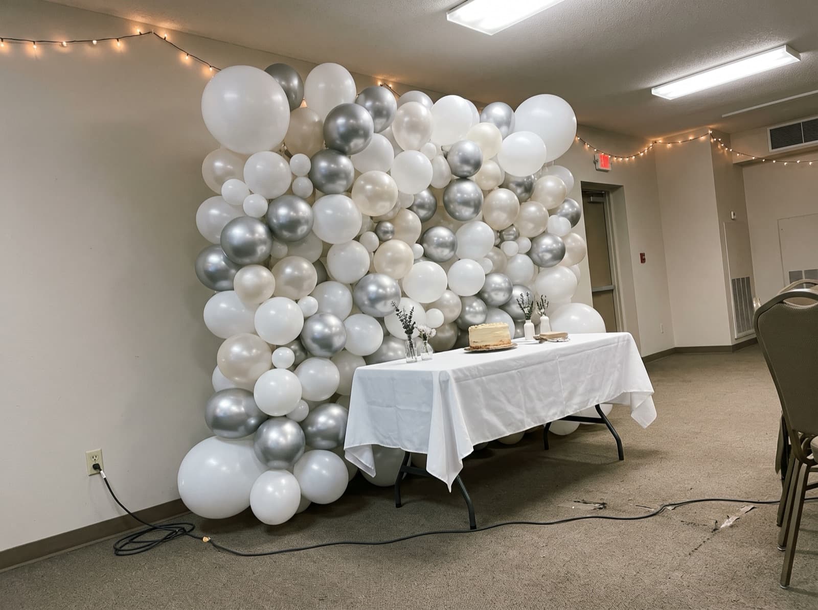 Organic balloon wall in white, pearl and silver behind a sweetheart table at a Houston event venue
